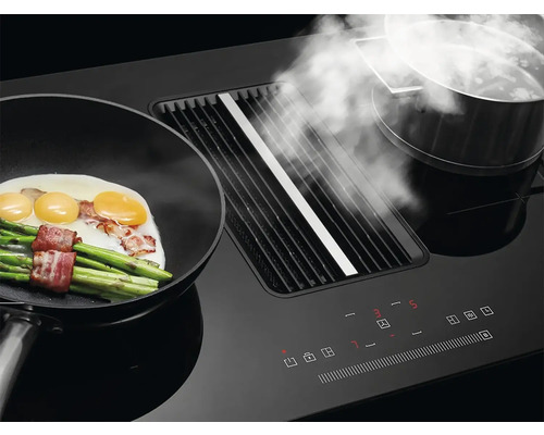 Čierny odsávač pár s panvicou, špargľou, vajcami a slaninou a hrncom s parou