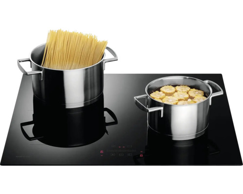 Čierna indukčná varná doska s hrncami s cestovinami a kukuricou