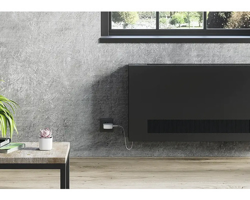 Obývacia izba s čiernym radiátorom na šedej stene