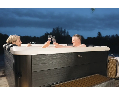 Dvaja ľudia si pripíjajú v drevenej vonkajšej vírivke nápojmi