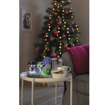 Dekoratívna vianočná scéna s osvetleným lyžiarskym svahom, šálkou, miskou a vianočným stromčekom v pozadí