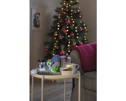 Dekoratívna vianočná scéna s osvetleným lyžiarskym svahom, šálkou, miskou a vianočným stromčekom v pozadí