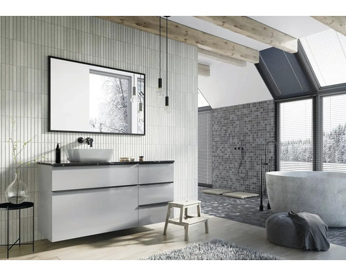 Svetlá kúpeľňa s umývadlom, zrkadlom, vaňou a mozaikovými obkladmi na stene.