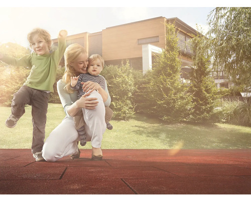 Matka s deťmi na ihrisku s bezpečnostnými podložkami pred domom a záhradou