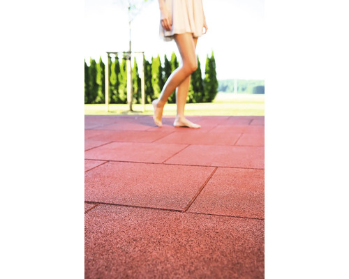 Gumové zámkové dlaždice na terase so ženou, ktorá po nich chodí naboso.