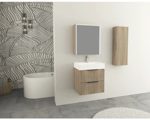 Kúpeľňa s umývadlom, zrkadlom, vysokou skriňou a vaňou pred vzorovanou tapetou.