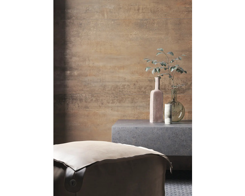 Pohľad do miestnosti s pufom, odkladacím stolíkom a dekoratívnymi predmetmi pred vzorovanou stenou