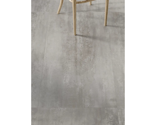 Dlažba s betónovým vzhľadom a nohy stoličky v popredí.