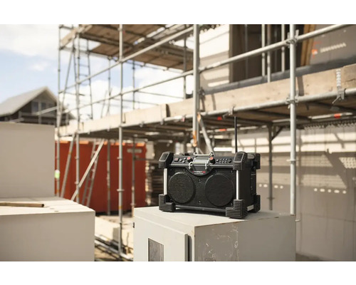 Stavebné rádio pred nedokončenou budovou s lešením