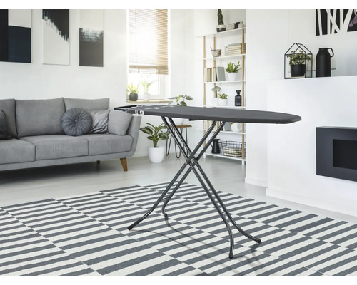 Žehliaca doska v obývacej izbe so svetlou pohovkou a kobercom.