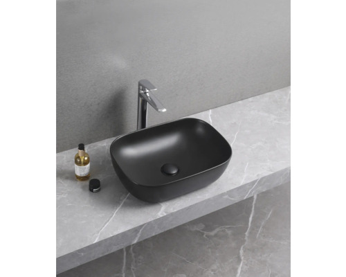 Čierne umývadlo na dosku s batériou na mramorovej doske