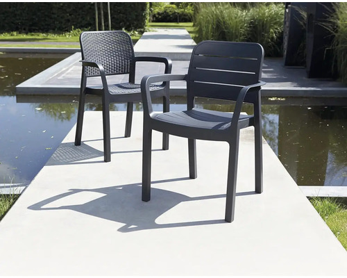 Dve sivé plastové záhradné stoličky s podrúčkami stoja vonku