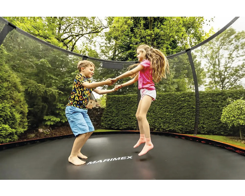 Dve deti skáču na záhradnej trampolíne s ochrannou sieťou.