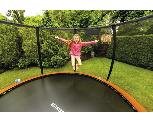 Dievča skáče na záhradnej trampolíne so sieťou