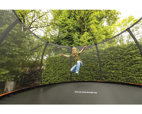 Dieťa skáče na trampolíne Marimex so sieťou v záhrade