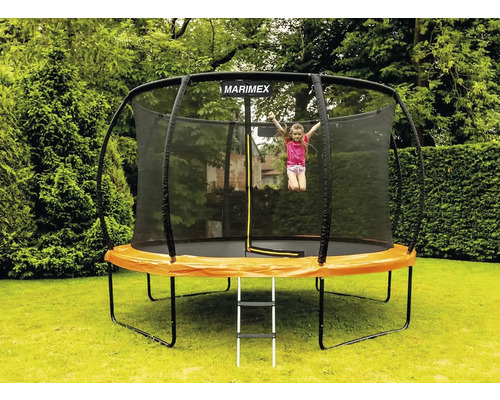 Dieťa skáče na záhradnej trampolíne so sieťou a rebríkom v záhrade. Logo Marimex.