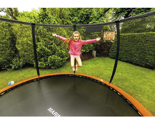 Dievča skáče na záhradnej trampolíne so sieťou