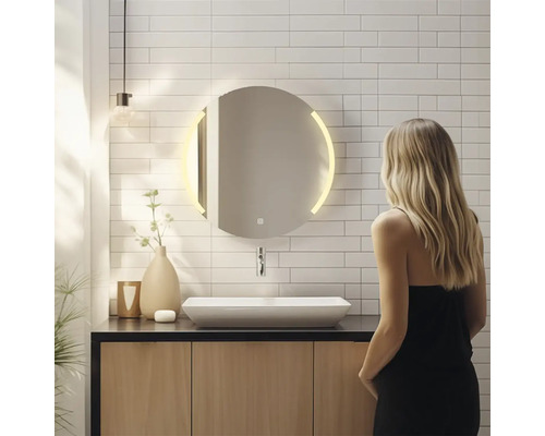 Kúpeľňa s okrúhlym zrkadlom so svetlom, umývadlom a ženou