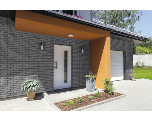 Fasáda domu s murovanou stenou, vchodovými dverami a garážovou bránou