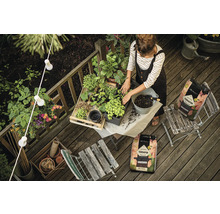 Žena sadí rastliny s kvetinovou zeminou na drevenej terase