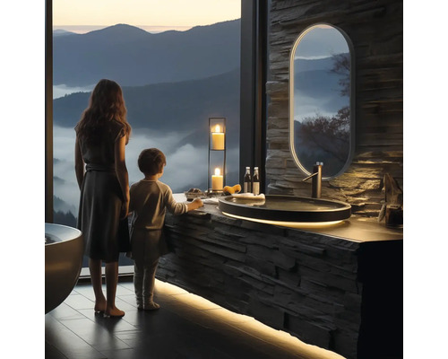 Svetlá kúpeľňa s kamenným umývadlom, zrkadlom a výhľadom na hory. Pri umývadle stojí žena a dieťa.