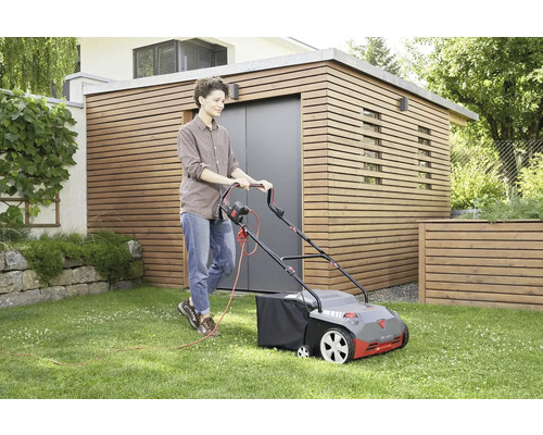 Žena používa elektrickú kosačku na trávu na trávniku