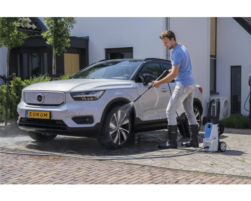 Muž čistí auto vysokotlakovým čističom pred domom