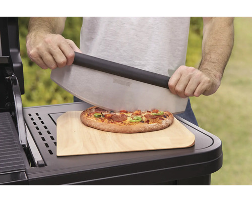 Osoba krája pizzu krájačom na pizzu na drevenej doske.