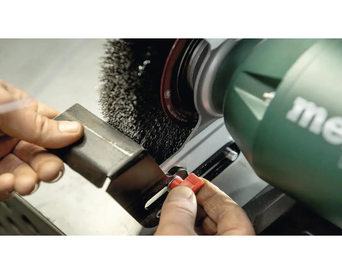 Kovový kus je opracovávaný drôtenou kefou na brúske