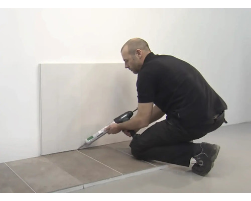 Osoba utesňuje stenu pomocou tesniacej pištole.