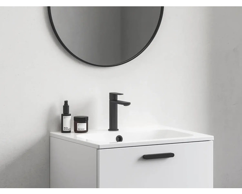 Pohľad na kúpeľňu s okrúhlym zrkadlom, skrinkou pod umývadlo, batériou a ošetrujúcimi produktmi