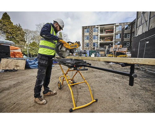 Stavebný robotník reže drevenú dosku vonku pokosovou píloul.