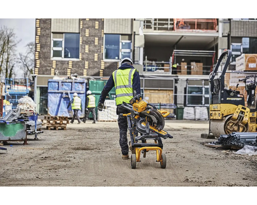 Stavebný robotník prepravuje pokosovú pílu na stavenisku