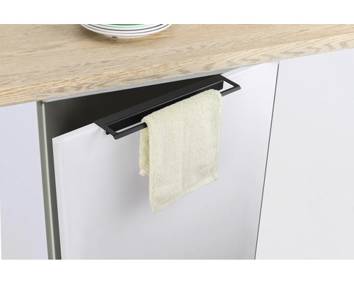 Čierny držiak na uteráky visí na dverách kuchynskej skrinky s uterákom.