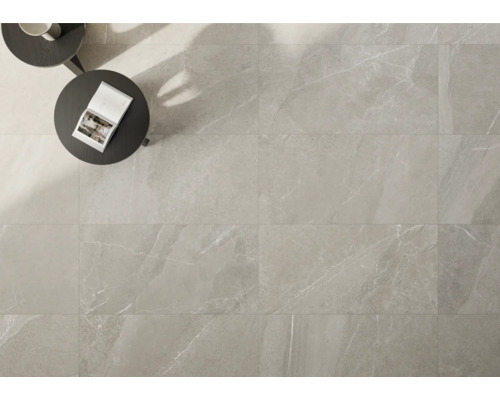 Svetlá podlahová dlažba s mramorovým vzhľadom položená, so stolom a knihou.