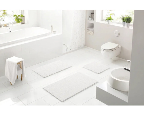 Svetlá kúpeľňa s vaňou, toaletou, umývadlom a kúpeľňovými predložkami