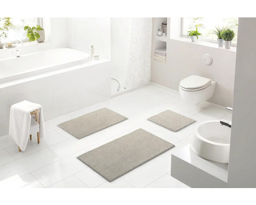 Svetlá kúpeľňa s vaňou, toaletou, umývadlom a súpravou troch kúpeľňových predložiek