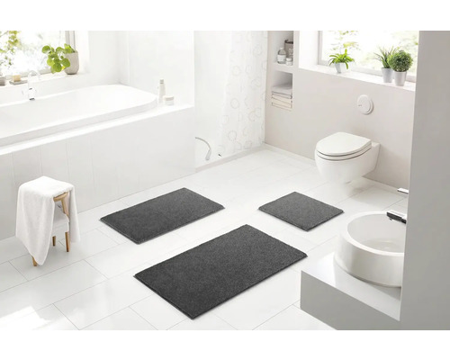 Svetlá kúpeľňa s vaňou, toaletou, umývadlom a súpravou troch sivých kúpeľňových predložiek