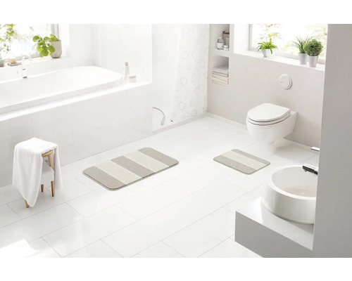 Svetlá kúpeľňa s vaňou, umývadlom, toaletou a pruhovanými kúpeľňovými predložkami