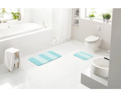 Moderná kúpeľňa s vaňou, toaletou, umývadlom a pruhovanými kúpeľňovými predložkami