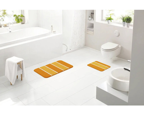 Kúpeľňa s vaňou, toaletou, umývadlom a dvoma kúpeľňovými predložkami s pruhovaným vzorom