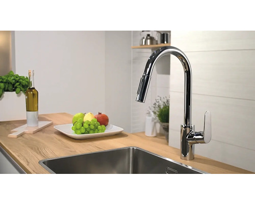 Kuchynská scéna s umývadlovou batériou, drezom a misou s ovocím na drevenej pracovnej doske