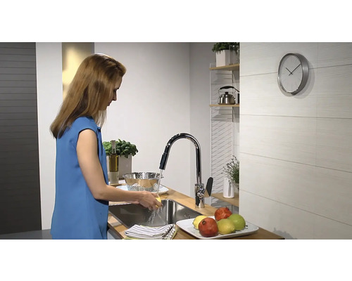 Žena umýva zeleninu pod kohútikom v modernej kuchyni