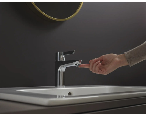 Ruka ovláda kovovú vodovodnú batériu na umývadle.