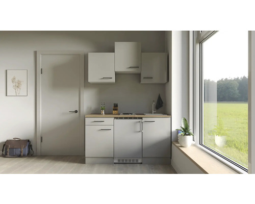 Malá kuchyňa s hornými skrinkami, drezom, varnou doskou a chladničkou vo svetlej miestnosti