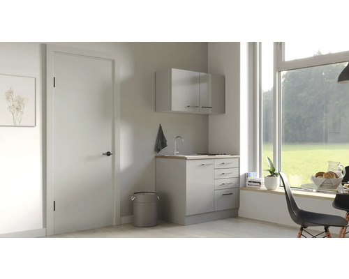 Svetlá práčovňa s umývadlom, spodnou skrinkou a závesnou skrinkou pod veľkým oknom.