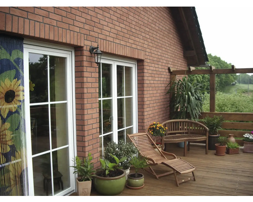 Terasa s drevenou palubovkou, záhradným nábytkom, rastlinami a tehlovou fasádou domu