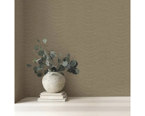 Detail steny s vlnitou tapetou, s vázou a knihami na stole.