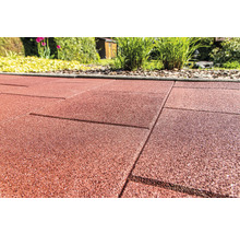 Detail červených gumových terasových dosiek v záhrade.