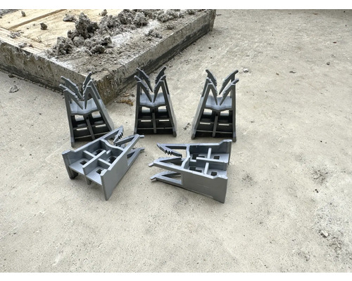 Päť dištančných prvkov debnenia na betónovej podlahe